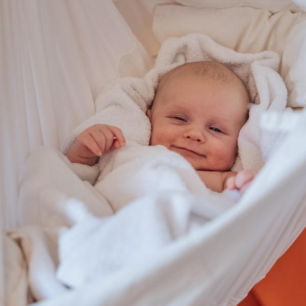 Lächelndes Baby in einer Hängematte im Babyhotel und Kinderhotel Babymio