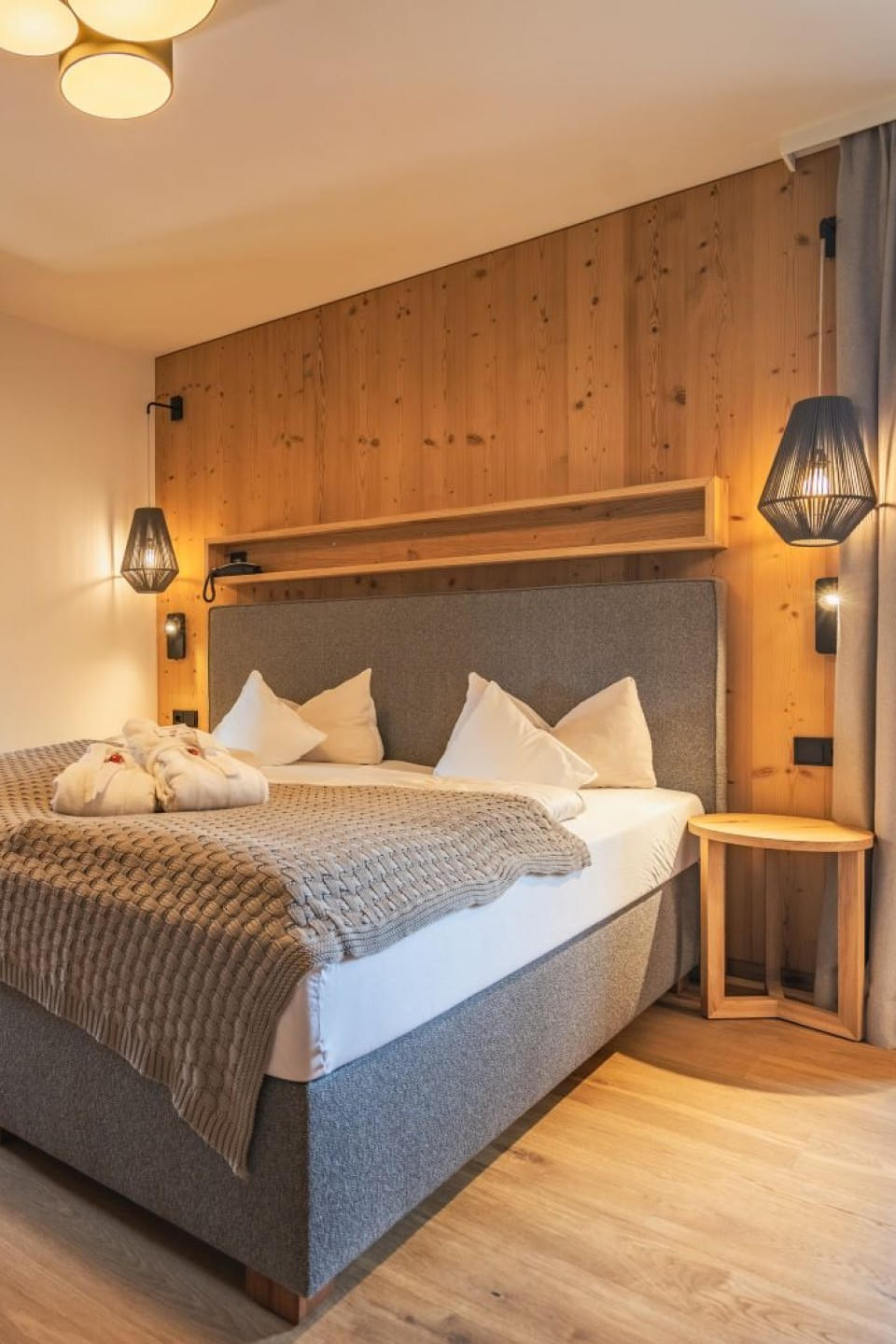 Gemütliches Doppelzimmer im Hotel Babymio mit Holzwand und Beleuchtung