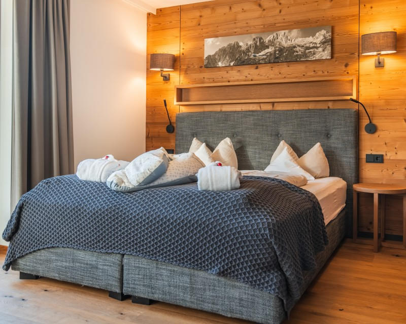 Junior Suite B SUP mit gemütlichem Doppelbett und Holzwand