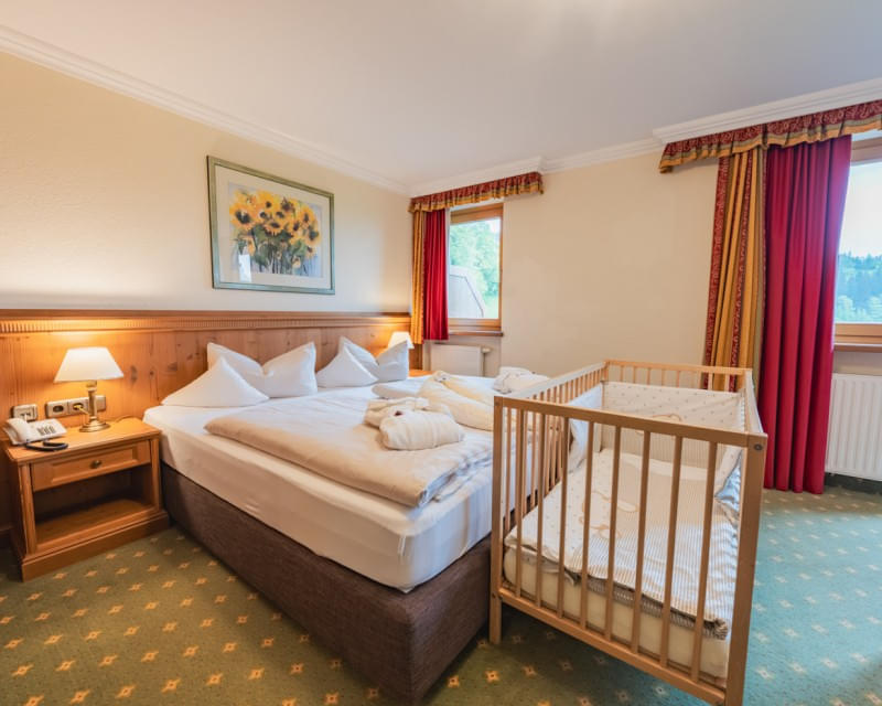 Doppelzimmer mit Babybett und gemütlicher Einrichtung