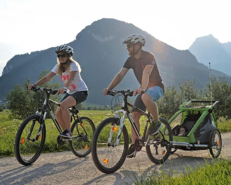 Familie beim Radfahren mit Kinderanhänger und Baby im Tal der Kitzbüheler Alpen