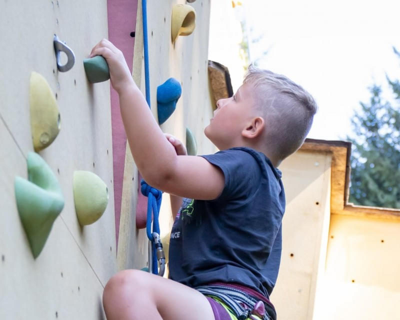 Kind beim Schnupperklettern an einer Kletterwand im Freien