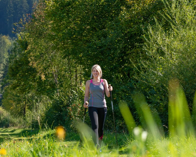 Frau beim Nordic Walking in grünen Sommerlandschaft