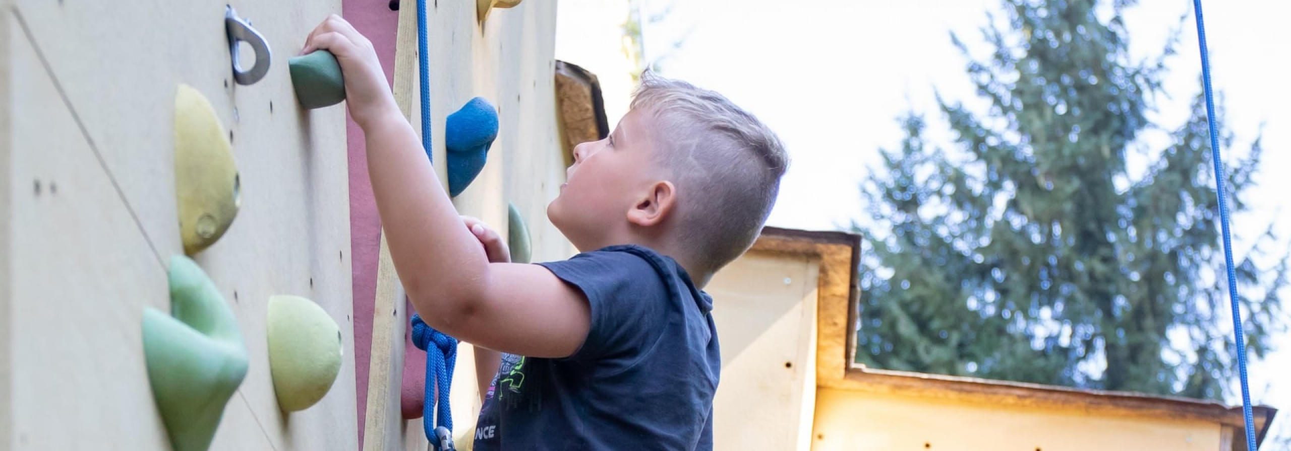 Kind beim Schnupperklettern an einer Kletterwand im Freien