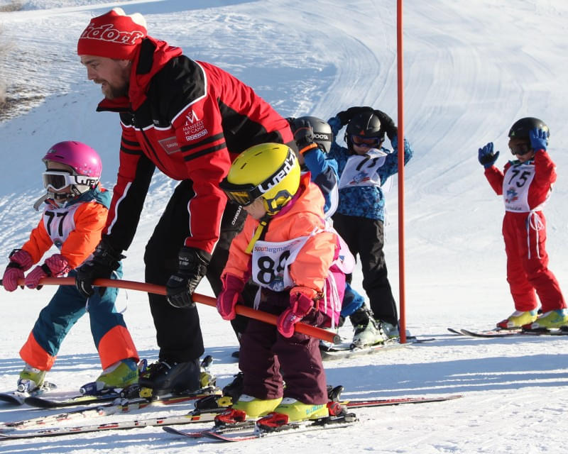 Kinder-Skikurs mit Skilehrer und Kindern im Mini-Skiclub