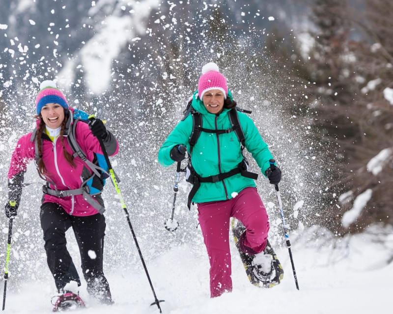 Zwei Frauen bei einer Schneeschuhwanderung im verschneiten Winterwald