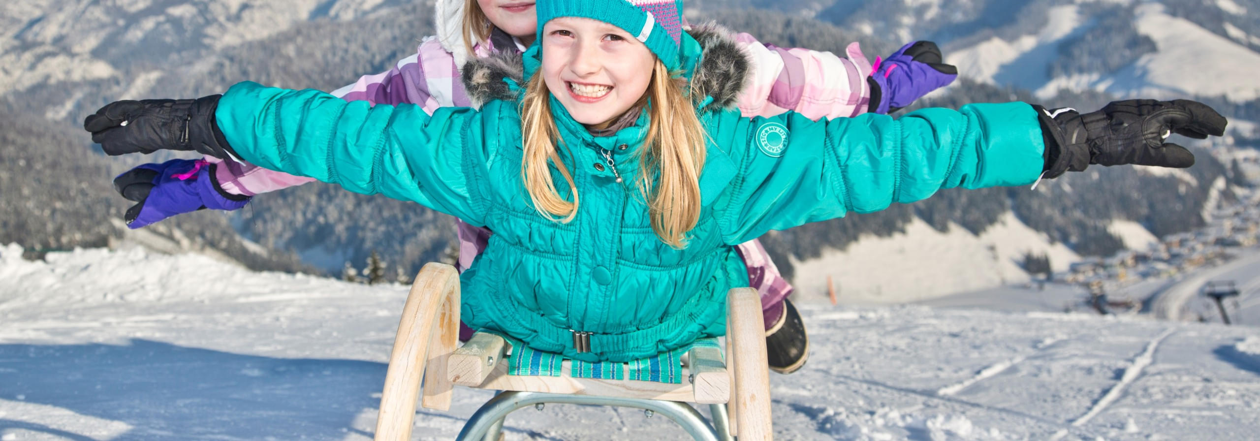 Kinder genießen das Rodeln im Schnee in den Kitzbüheler Alpen