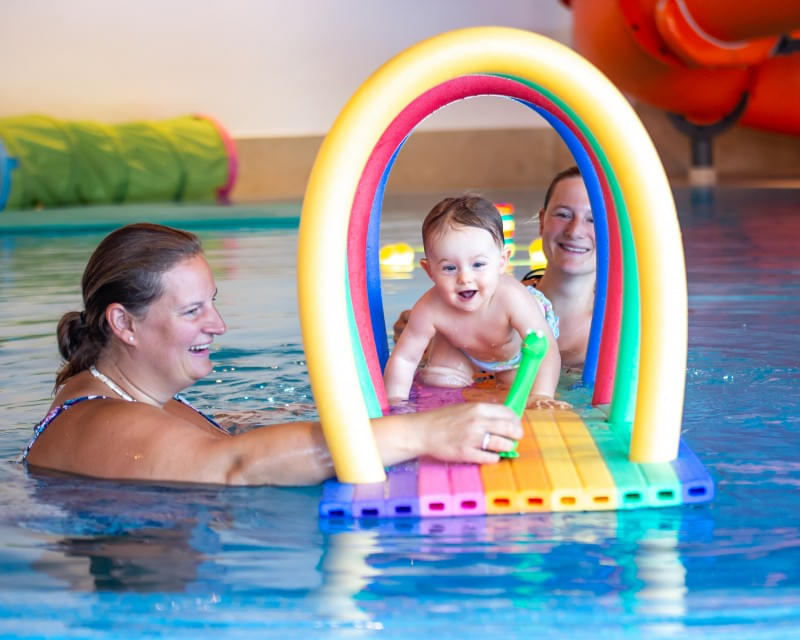 Mutter probiert Baby schwimmen zu lernen im Hallenschwimmbad des Hotel Babymio