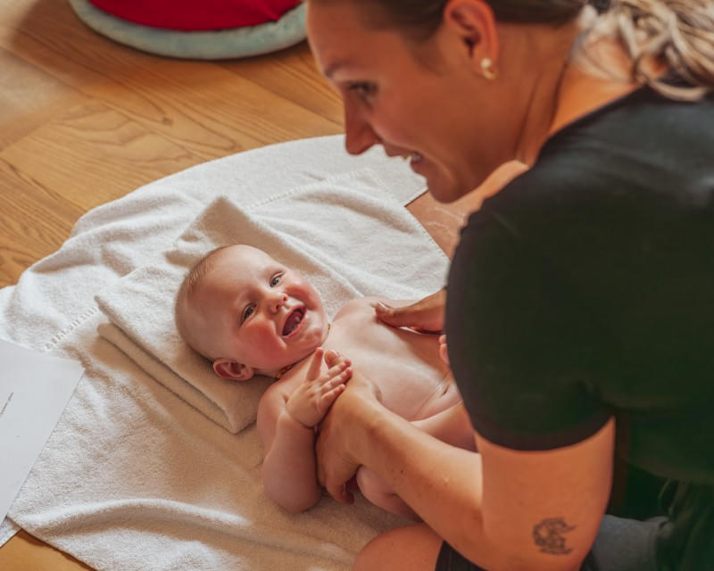 Lachendes Baby bei der Babymassage im Hotel