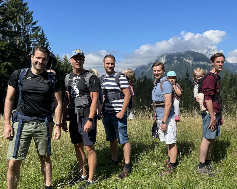 Väter wandern mit Babys in Tragen in der Berglandschaft des Kaisergebirges