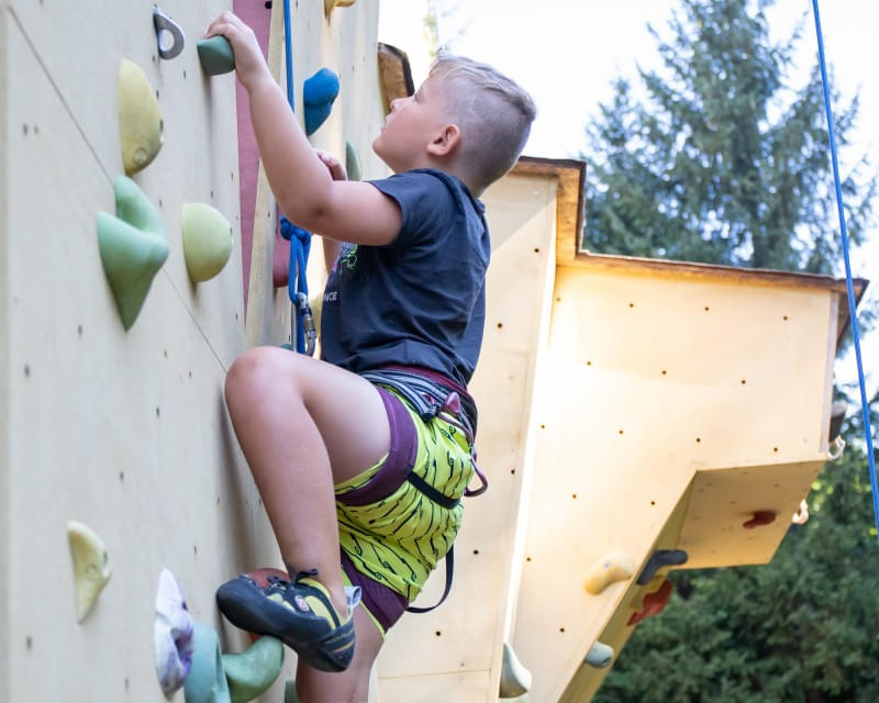 Junge beim Schnupperklettern an einer Kletterwand im Freien