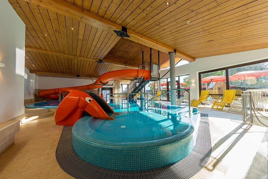 Innenansicht des Hallenschwimmbads mit Wasserrutsche und Elefantenrutsche im Hotel
